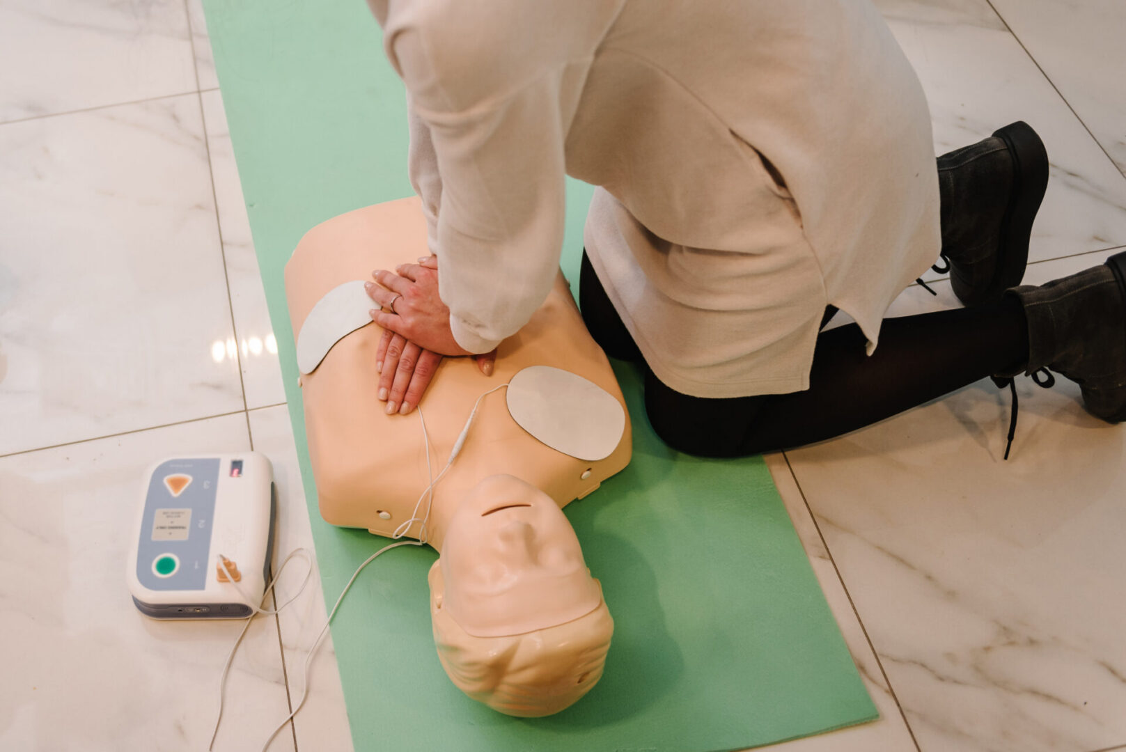 Indirect heart massage. Automated external defibrillator device, training dummy mannequin. Automatic defibrillator in conducting basic cardiopulmonary resuscitation. Demonstrating chest compressions