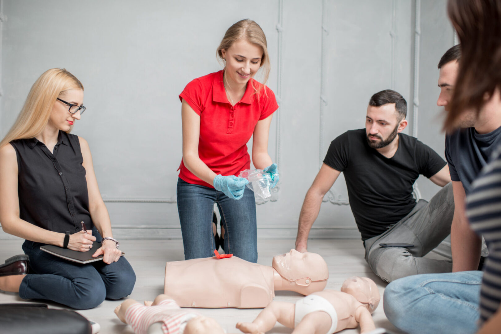 Young woman instructor showing valve for artificial respiration during the first aid group training indoors