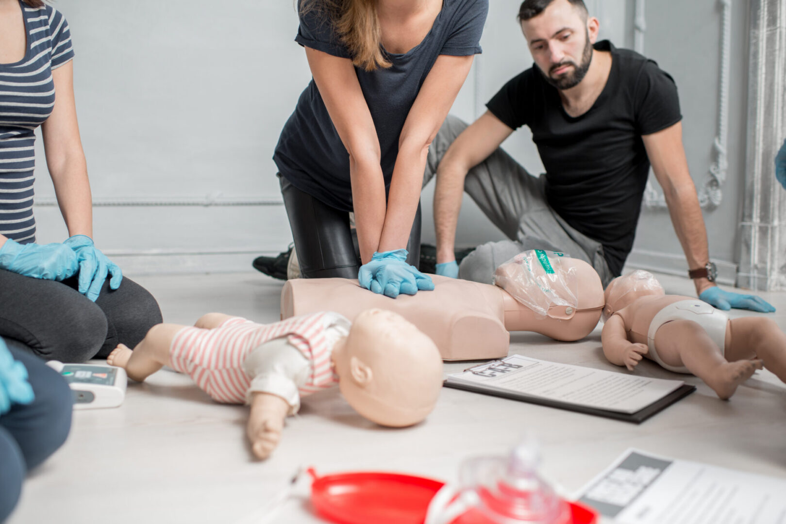 Group of people learning how to make first aid heart compressions with dummies during the training indoors